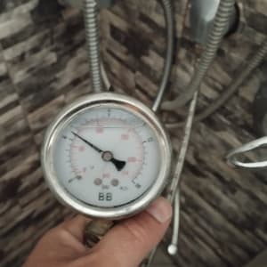 מד לחץ מים עם צינורות מתכת על קיר