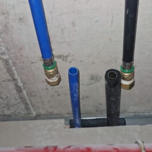 צינורות כחולים ושחורים עם מחברים על קיר בטון