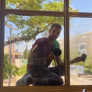 אדם מנקה חלון עם ספוג ומגבת