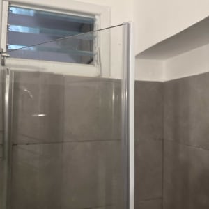 זכוכית מקלחון עם קיר אריחים וחלון קטן