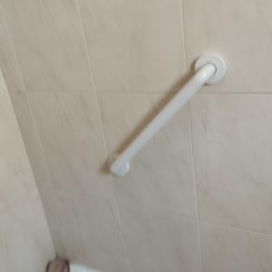 ידית אחיזה לבנה מותקנת על קיר אריחים