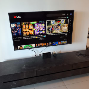 טלוויזיה על קיר עם מסך יוטיוב, קונסולה על שידה