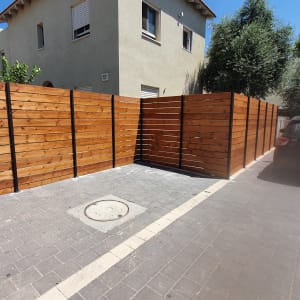 גדר עץ חומה עם עמודים שחורים בחניה