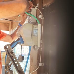 חשמלאי מתקין כבל ירוק לתוך קופסת חשמל