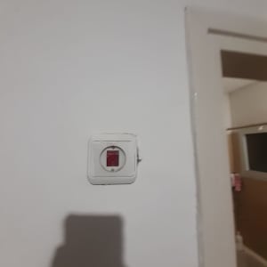 מתג חשמלי עם כיסוי לבן על קיר לבן