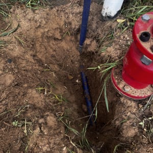חפירה באדמה עם צינור כחול וברז אדום