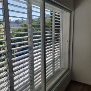 תריסים לבנים עם אבק עליהם ליד חלון