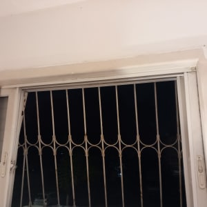 חלון עם סורגי מתכת ומסגרת לבנה