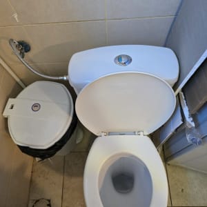 אסלה פתוחה עם פח אשפה בחדר שירותים קטן