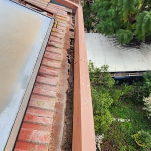 רעפים אדומים על גג עם חלודה ונזק לאורך הקצה