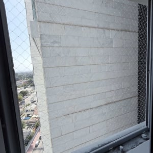 התקנת רשת שקופה נגד יונים בחלון בבניין מגורים גבוה