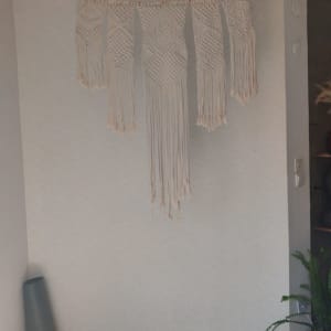 קיר עם טפט בהיר ודוגמת מקרמה תלויה