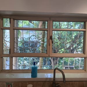 חלון אלומיניום עם סורג ונוף ירוק בחוץ