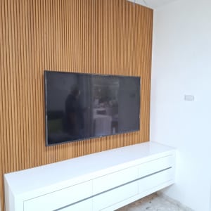 טלוויזיה מותקנת על קיר עץ עם ארונית לבנה