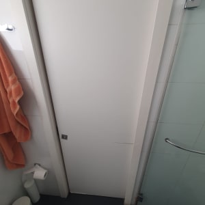 דלת הזזה לבנה בחדר אמבטיה עם מגבת כתומה