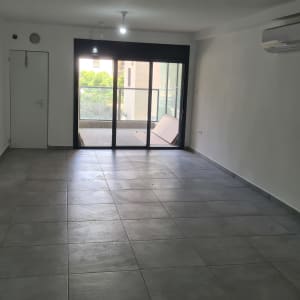 חדר ריק עם קירות לבנים ורצפת אריחים אפורה