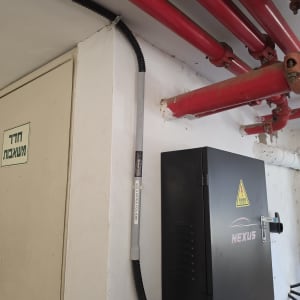 ארון חשמל עם צינורות אדומים על קיר לבן