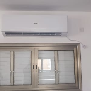 מזגן מותקן על קיר מעל חלון עם תריסים