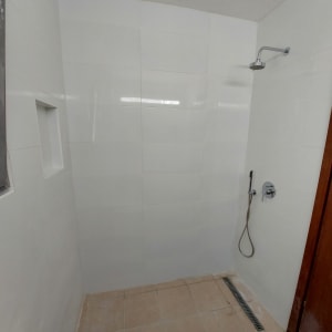 חדר רחצה עם אריחים חדשים ומקלחת מותקנת