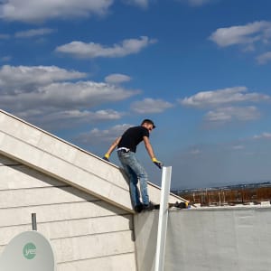 אדם על גג עם לוח לבן וכלי עבודה