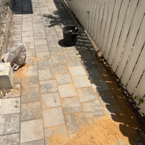 כלי עבודה ודלי על שביל מרוצף עם חול