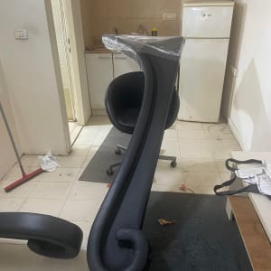 רהיטים עטופים בניילון בחדר ריק עם מקרר וכיור