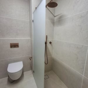 מקלחון זכוכית חלבית קבוע בחדר רחצה מודרני עם אביזרי נחושת