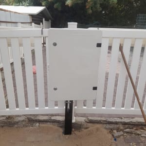 ארון חשמל לבן מותקן על גדר עץ לבנה