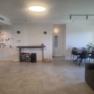 חדר מגורים עם שולחן אוכל וכיסאות, קיר לבן ותאורה