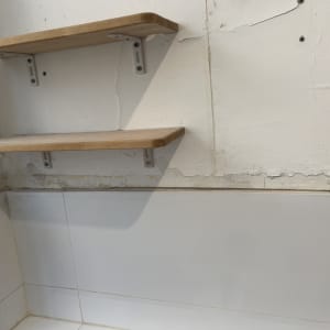מדף עץ על קיר עם אריחים לבנים