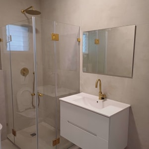 חדר אמבטיה עם מקלחון זכוכית וברזים מוזהבים