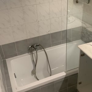 אמבטיה עם אריחים אפורים ולבנים, ברז ומקלחת