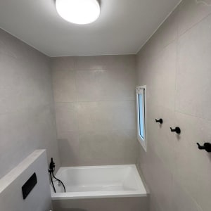 חדר אמבטיה משופץ עם אמבטיה, שירותים ותאורה חדשה