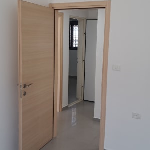 קיר צבוע בלבן עם דלת עץ פתוחה