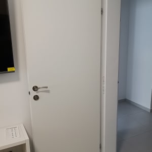 דלת לבנה עם ידית מתכת כסופה פתוחה למחצה