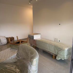 רהיטים עטופים בניילון בחדר ריק, מוכן להובלה