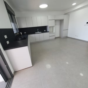 מטבח נקי עם ארונות לבנים ומשטח עבודה כהה