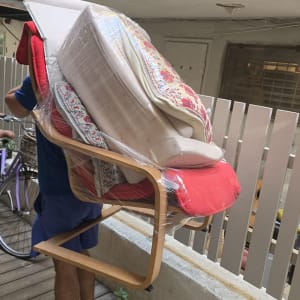 אדם נושא כיסא עטוף בניילון במעבר חיצוני
