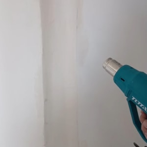 אקדח חום על קיר לבן בעבודת תיקון