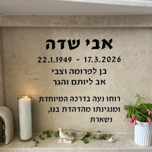 מצבה עם נר זיכרון ופרחים