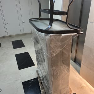 רהיטים עטופים בניילון על עגלת הובלה ליד מעלית