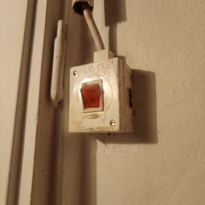 מתג חשמלי על קיר עם חוטים חשופים