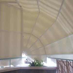 סוכך לבן מתוח מעל מרפסת עם צמחייה