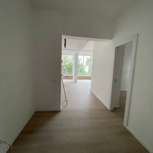 קירות גבס לבנים בחדר ריק עם רצפת עץ