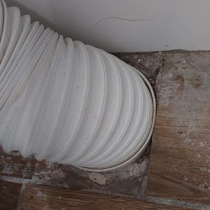 צינור גמיש לבן מחובר לרצפה ליד קיר