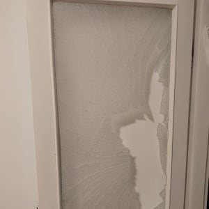 דלת עם זכוכית שבורה וסדוקה בחלקה התחתון