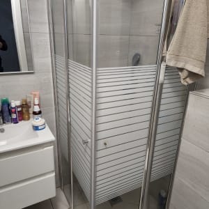 מקלחון זכוכית בחדר אמבטיה עם מגבות ותמרוקים