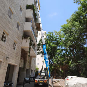 מנוף ליד בניין מגורים עם עצים מסביב