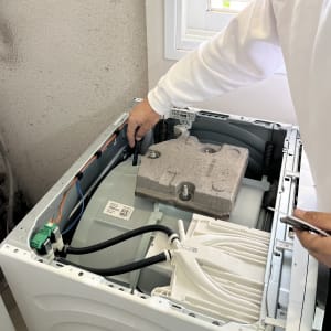 אדם מתקן מכונת כביסה עם כלים חשמליים