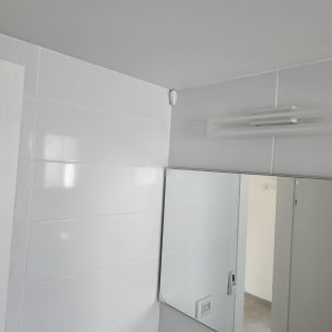 שלט מזגן תלוי על קיר לבן בחדר אמבטיה